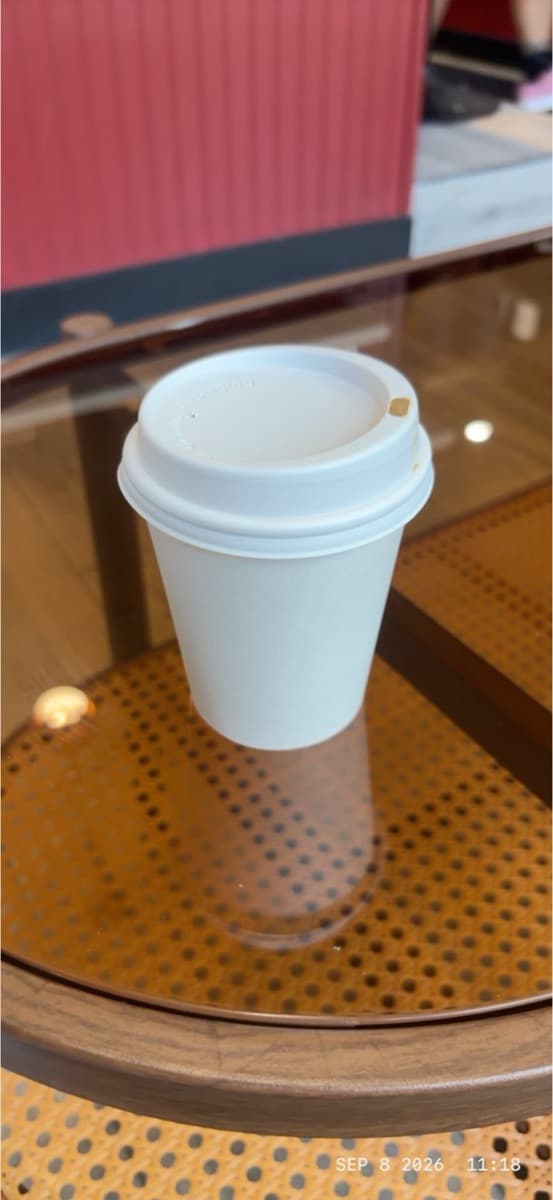 A paper cup of cortado on a café table